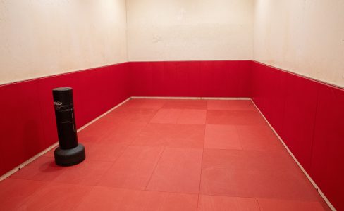 the walls of the combative arts room are lined with red mats and theres a punching bag inside