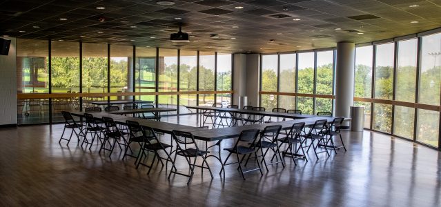 the multi activity room has several tables and chairs and large windows to let in light