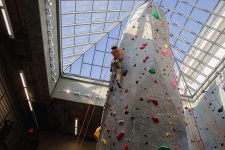 someone climbing up a climbing wall with multiple different colored handles 